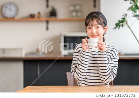 自宅のリビングでホットドリンクを飲む小学生,中学生の女の子 131672572