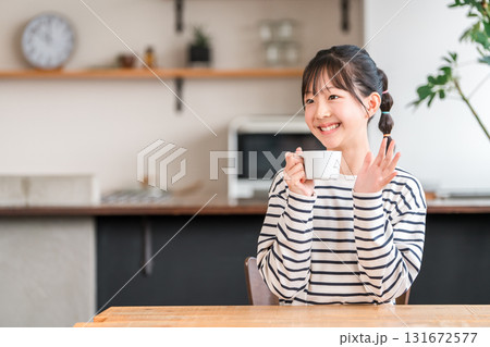 自宅のリビングでホットドリンクを飲む小学生,中学生の女の子 131672577