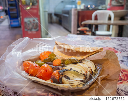 【ヨルダン】首都アンマンのレストランでテイクアウトした焼きトマトや玉ねぎが添えられたケバブプレート 131672731