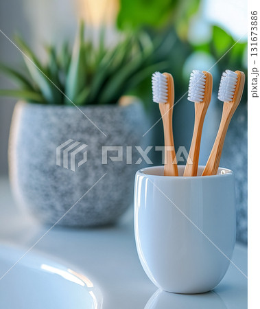 Natural bamboo toothbrushes in a stylish holder next to green plants in a modern bathroom setting during daylight 131673886