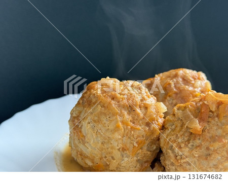 Three steaming meatballs with sauce on plate. Meatballs with rice and onions simmered in tomato sauce. Delicious and healthy home cooking. Three steaming meatballs with sauce on plate. Meatballs with rice and onions simmered in tomato sauce. Delicious and healthy home cooking. 131674682