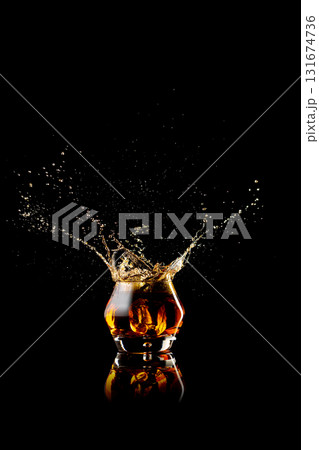 Whiskey splash captured in dynamic motion with amber reflections Whiskey splash captured in dynamic motion with amber reflections 131674736
