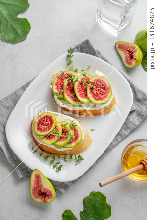 Sweet toasts with fresh figs, cheese, thyme, and honey on a light background. Sweet toasts with fresh figs, cheese, thyme, and honey on a light background. 131674825