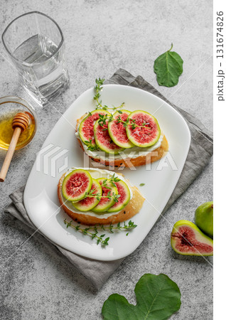 Sweet toasts with fresh figs, cheese, thyme, and honey on a gray background. Sweet toasts with fresh figs, cheese, thyme, and honey on a gray background. 131674826