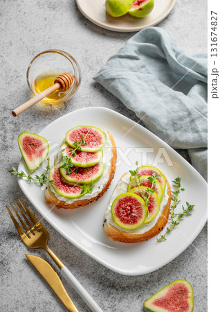 Sweet toasts with fresh figs, cheese, thyme, and honey on a gray background. 131674827