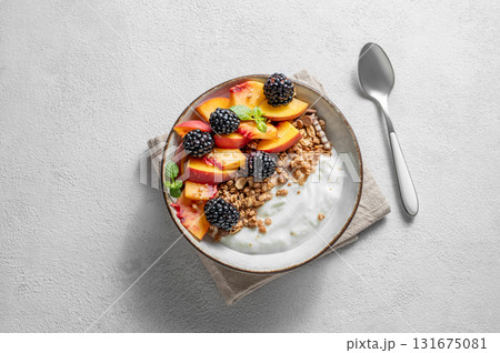 Natural Greek yogurt with granola or muesli, peach and blackberry in a bowl on a light background Natural Greek yogurt with granola or muesli, peach and blackberry in a bowl on a light background 131675081