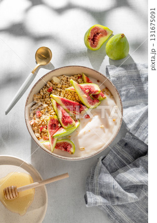 Natural yogurt with granola, figs and honey in a bowl on a light background Natural yogurt with granola, figs and honey in a bowl on a light background 131675091