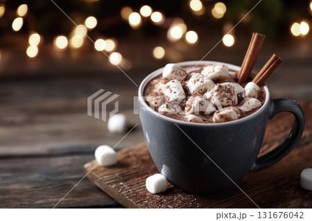 Cup of hot chocolate with marshmallows and cinnamon sticks on rustic wooden table, Christmas lights blurred in background 131676042