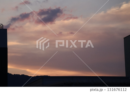 茜色の夕空とシルエットの建物と山の風景 131676112