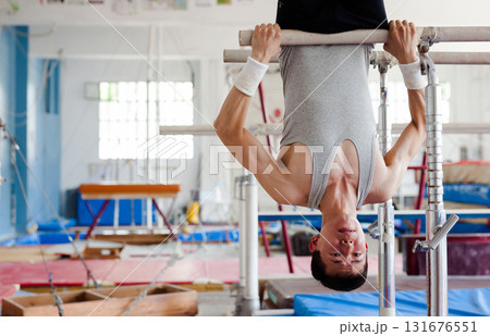 Focused gymnast practicing on parallel bars in gym 131676551