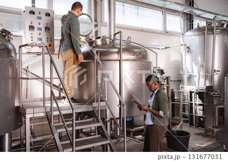 Brewery workers inspecting production quality control with digital tablet 131677031