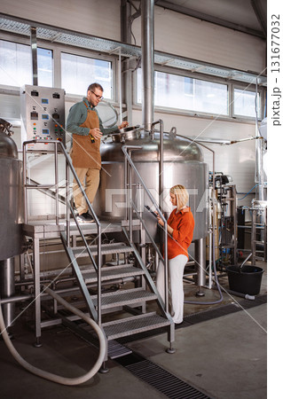 Brewery workers monitoring beer brewing process 131677032