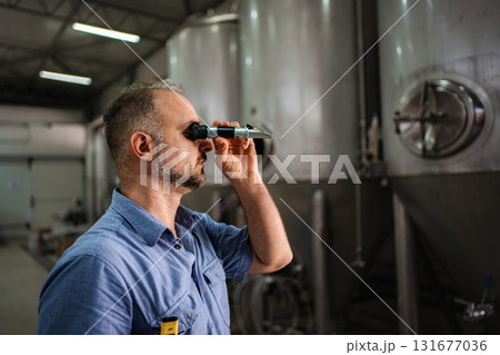 Man using refractometer checking beer quality at brewery Man using refractometer checking beer quality at brewery 131677036