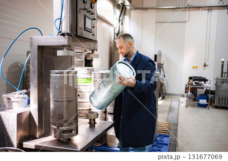 Man working in brewery with beer keg filling machine 131677069