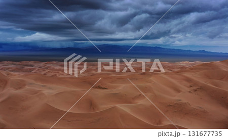Sand dunes with storm clouds at sunset in desert Sand dunes with storm clouds at sunset in desert 131677735