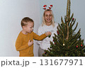 Christmas, house and hug with mother, son and bonding together with gift, decoration and care in lounge. Xmas tree, family and parent with boy, embrace and present with happiness, holiday and festive 131677971