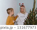 Christmas, house and hug with mother, son and bonding together with gift, decoration and care in lounge. Xmas tree, family and parent with boy, embrace and present with happiness, holiday and festive 131677973