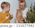 Christmas, house and hug with mother, son and bonding together with gift, decoration and care in lounge. Xmas tree, family and parent with boy, embrace and present with happiness, holiday and festive 131677982