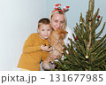 Christmas, house and hug with mother, son and bonding together with gift, decoration and care in lounge. Xmas tree, family and parent with boy, embrace and present with happiness, holiday and festive 131677985