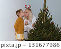 Christmas, house and hug with mother, son and bonding together with gift, decoration and care in lounge. Xmas tree, family and parent with boy, embrace and present with happiness, holiday and festive 131677986