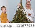 Christmas, house and hug with mother, son and bonding together with gift, decoration and care in lounge. Xmas tree, family and parent with boy, embrace and present with happiness, holiday and festive 131677988