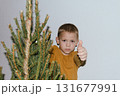 Festive baby boy in yellow sweater getting ready to decorate the Christmas tree, creating a warm holiday atmosphere for celebrating with loving family members tonight. 131677991