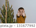 Festive baby boy in yellow sweater getting ready to decorate the Christmas tree, creating a warm holiday atmosphere for celebrating with loving family members tonight. 131677992