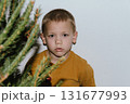 Festive baby boy in yellow sweater getting ready to decorate the Christmas tree, creating a warm holiday atmosphere for celebrating with loving family members tonight. 131677993