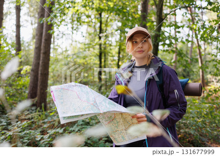 Female hiker in forest with map for navigation Female hiker in forest with map for navigation 131677999