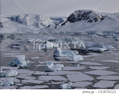 Antarctica ocean with scattered icebergs and mountains 131678122