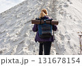Back view of hiker woman climbing sandy hill with backpack 131678154