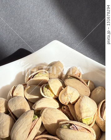 Pistachios in a white bowl. Bowl of pistachios on dark background. Pistachios in a white bowl. Bowl of pistachios on dark background. 131678294