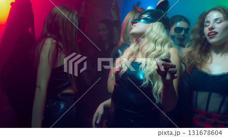 Group of people in costumes dancing under neon lights at club Group of people in costumes dancing under neon lights at club 131678604