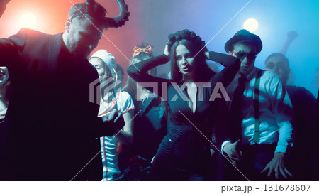 Young woman in black dress dancing at nightclub Halloween party with dramatic lights 131678607