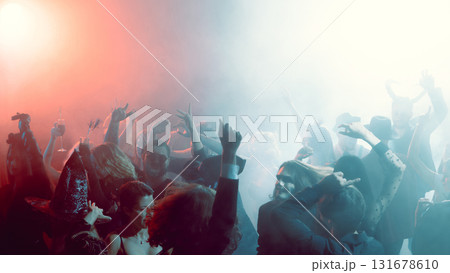 Smiling young woman with arms raised dancing in Halloween party nightclub 131678610