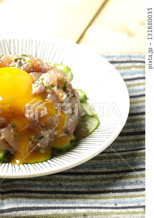 イナダのユッケの上の卵黄を割る 131680035