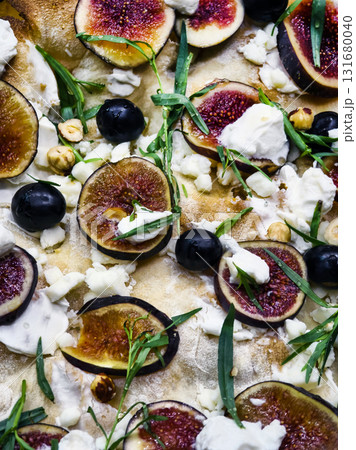 Delicious fig and cheese pizza topped with herbs and nuts served fresh 131680040