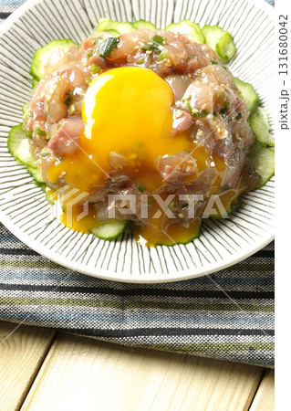 イナダのユッケの上の卵黄を割る 131680042