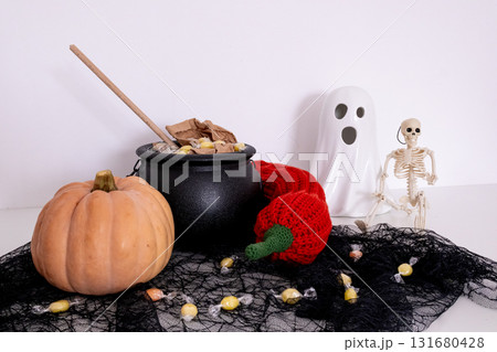 Halloween decor with pumpkin, candy cauldron, ghost, and skeleton figures 131680428