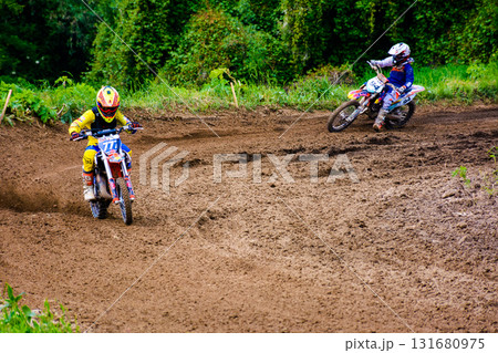 uzhhorod, ukraine - may 21, 2017: junior mx rider turns on a corner. motocross track through forest. extreme sport with flying dirt during accelerating 131680975