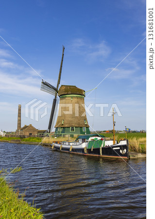 Traditional Dutch windmill and boat on canal in Opmeer 131681001