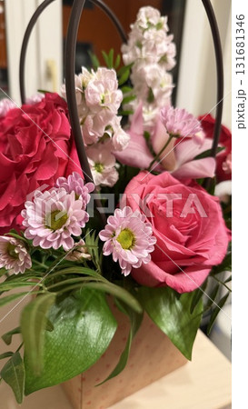 Bouquet of pink and red flowers with green leaves in decorative basket indoors 131681346