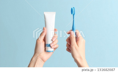 水色背景に歯ブラシと歯磨き粉のチューブを持つ女性の手 131682087