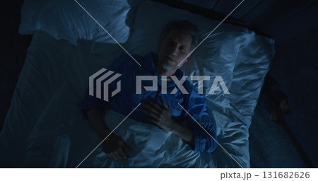 Gray Haired Mature Man Lies in Bed Unable Sleep, Lost in Thoughts About Aging and Solitude Gray Haired Mature Man Lies in Bed Unable Sleep, Lost in Thoughts About Aging and Solitude 131682626