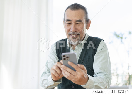 スマートフォンを操作する笑顔の70代の男性 131682854