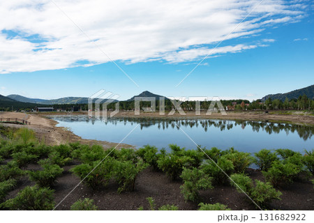 Scenic view of a lake surrounded by mountains and greenery. Scenic view of a lake surrounded by mountains and greenery. 131682922