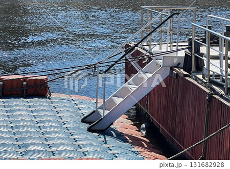 Staircase leading to floating dock on a calm waterfront during bright daylight 131682928