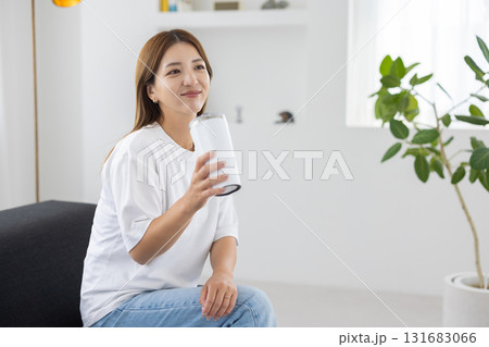 タンブラーを手にソファに座る若い女性 131683066