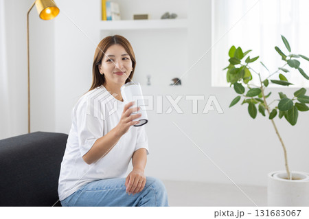 タンブラーを手にソファに座る若い女性 タンブラーを手にソファに座る若い女性 131683067