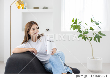 タンブラーを手にソファに座る若い女性 タンブラーを手にソファに座る若い女性 131683071
